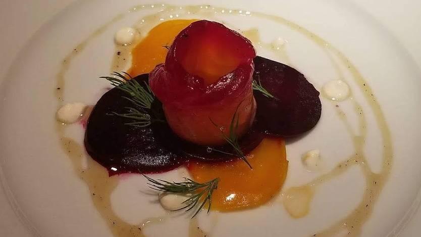 A plated dish of colorful beets, carrot ribbons, and fresh herbs